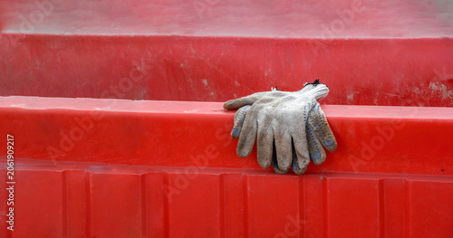 Work gloves resting on red industrial container surface