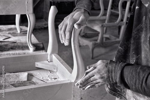 Foto Black and white photo of craftsman sanding wooden furniture leg by hand