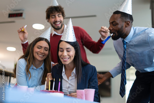Coworkers celebrating office birthday party with cake and candles