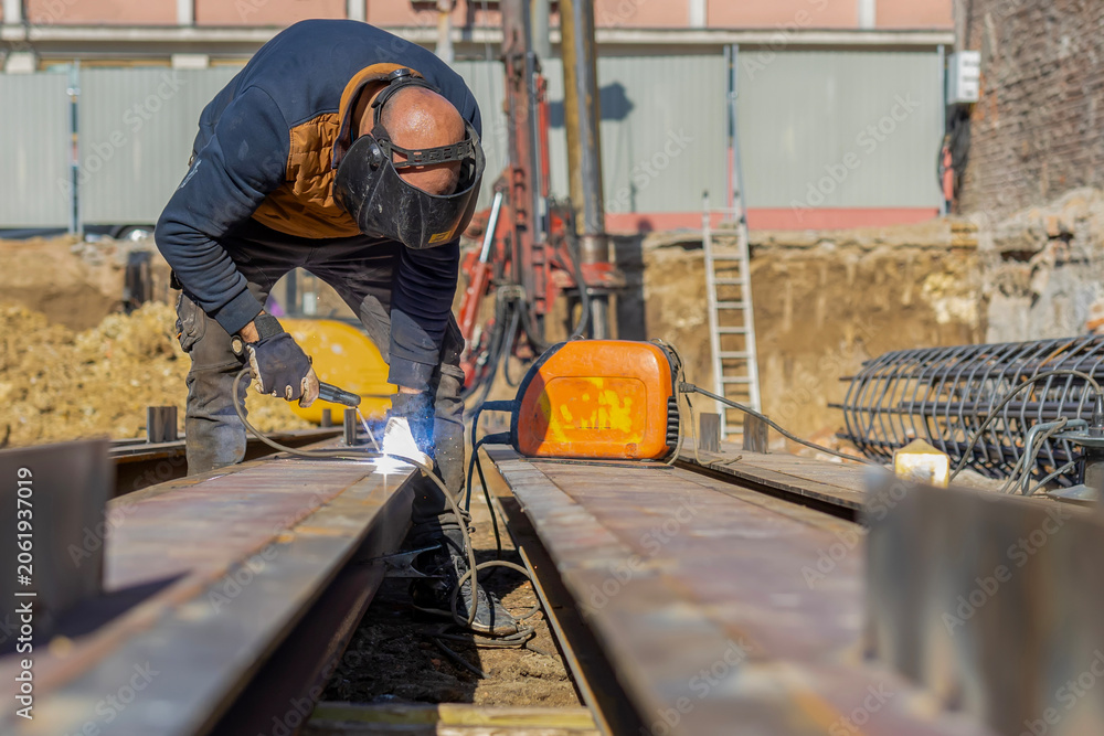 Fototapeta premium Construction worker welding metal beam at building site