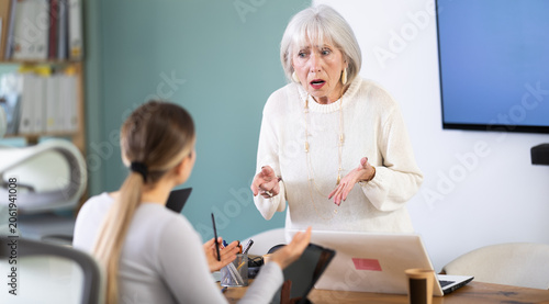 Obraz na plátně Woman does not cope with her work duties at tablet, and employee is reprimanded by her mature superiors