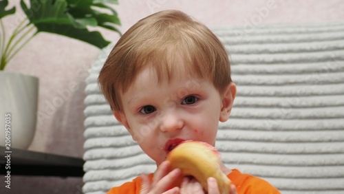 A portrait of a beautiful little boy holding a dessert—a donut covered in icing. A sweet expression on the girl's face as she enjoys a sweet donut. Diet for weight loss. Eating fast food and unhealth