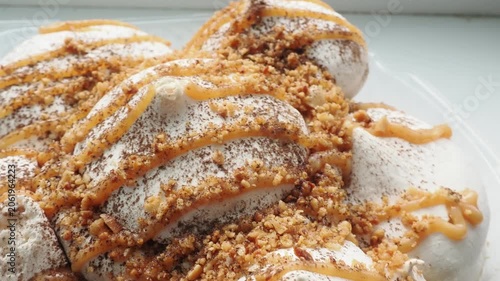 Meringue cake drizzled with caramel. A delicious dessert. A close-up of a multi-layered cake with nuts, cream, and almonds
