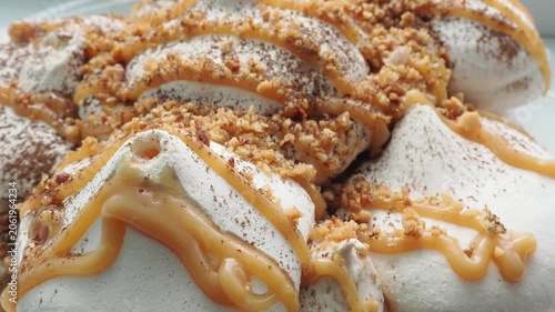 Meringue cake drizzled with caramel. A delicious dessert. A close-up of a multi-layered cake with nuts, cream, and almonds