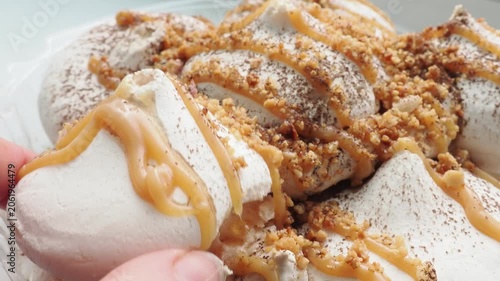 Meringue cake drizzled with caramel. A delicious dessert. A close-up of a multi-layered cake with nuts, cream, and almonds