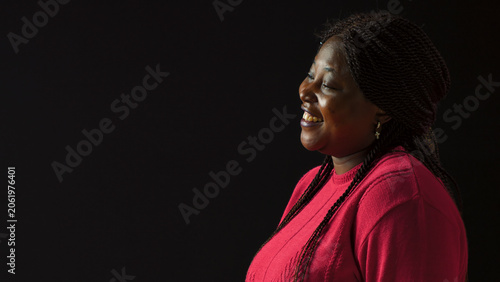 Fotografija Beautiful woman giggling during picture shoot while dressed stylishly in pink, with laughing vibrant female fashionista model on isolated black background