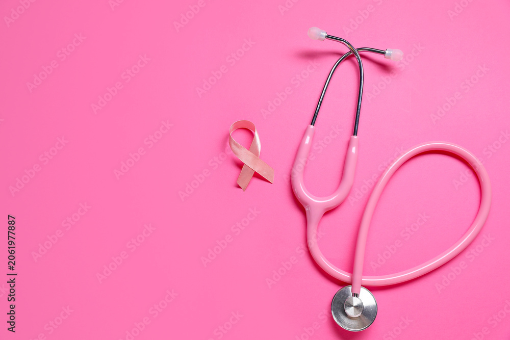 Fototapeta premium Pink awareness ribbon and stethoscope on color background, flat lay. Space for text