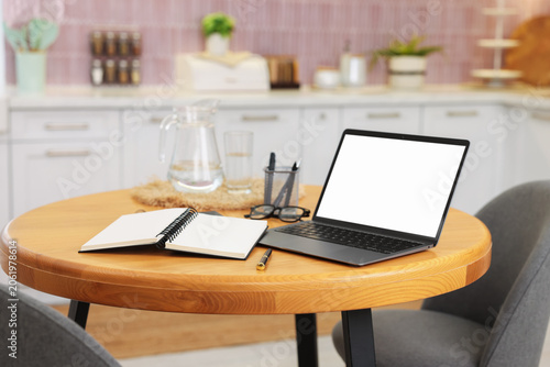 Comfortable home workplace with laptop on wooden table in kitchen