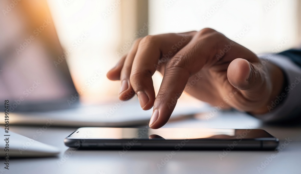 Fototapeta premium Hand using tablet in office, typing on touchscreen device