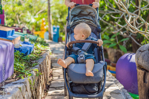 Woman pushing baby stroller through traditional Mexican cemetery during Day of the Dead, exploring colorful cultural heritage with her infant in Mexico