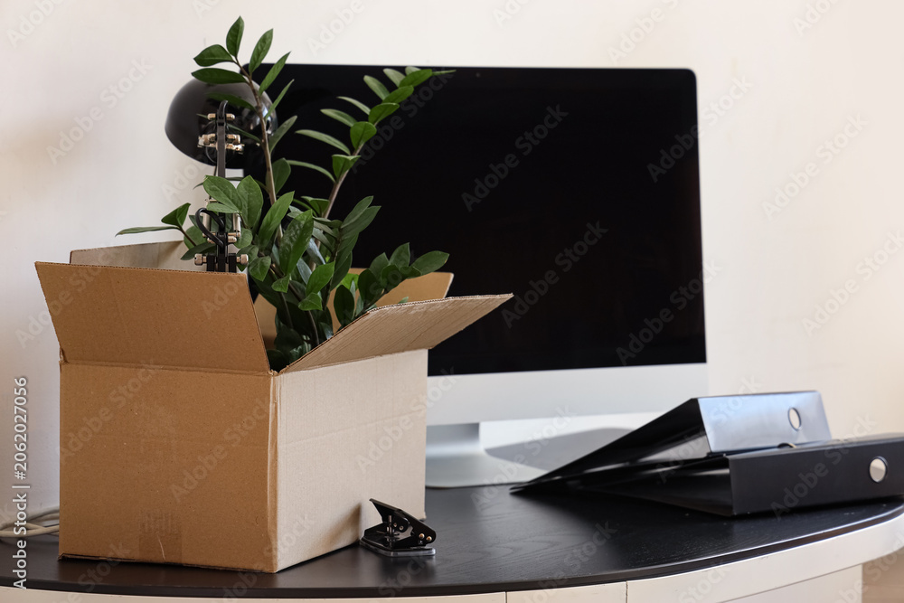 Obraz premium Workplace with computer, cardboard box and things in office on moving day