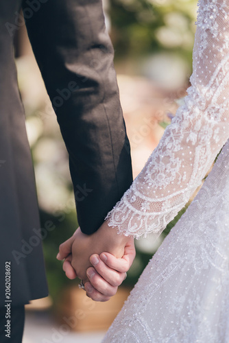 Close up of bride and groom holding hands at a romantic wedding ceremony
