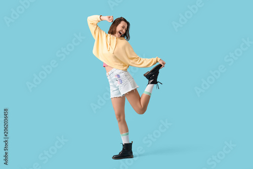 Young woman dancing on blue...