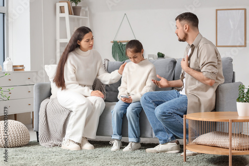 Картината върху платно Parents apologizing to their offended daughter on sofa at home