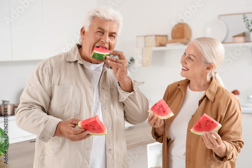 Mature couple eating watermelon in kitchen