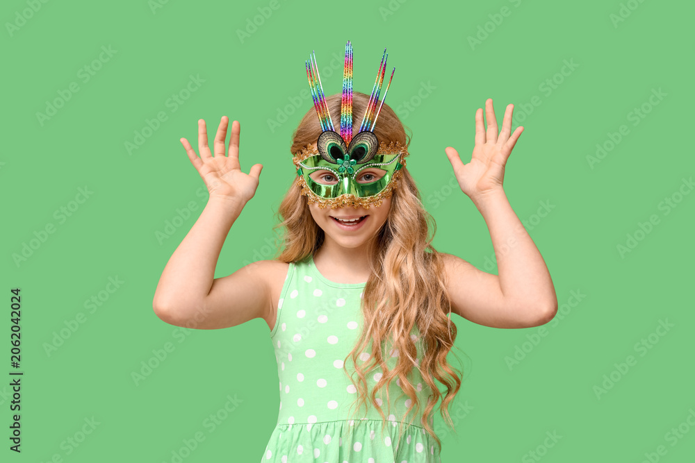 Fototapeta premium Adorable little girl wearing carnival mask on green background