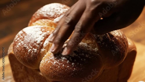 Close-Up Of A Golden-Brown Brioche Loaf Being Gently Pinched With Flour By A Human Hand In A Cooking Scene