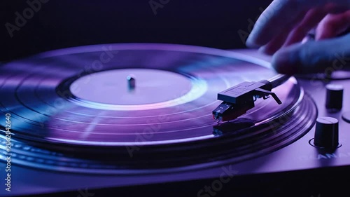 Close-Up Of A Hand Gently Lowering A Stylus Onto A Vinyl Record On A Turntable With Modern Purple And Blue Lighting In A Studio Setting
