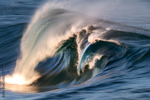 Bild auf Leinwand Photograph of a powerful ocean wave breaking over a submerged reef at sunset on the south coast of New South Wales, Australia, captured with a slow shutter speed to create a dreamlike effect