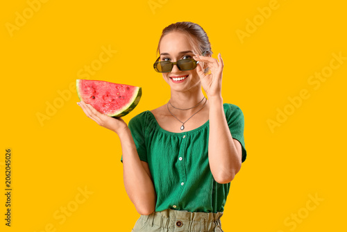 Young woman with fresh watermelon on yellow background