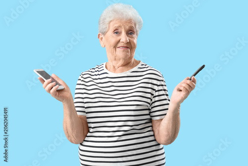 Senior woman with mobile phones on blue background
