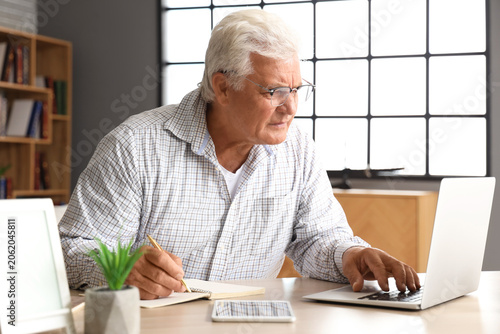 Senior man with notebook us...