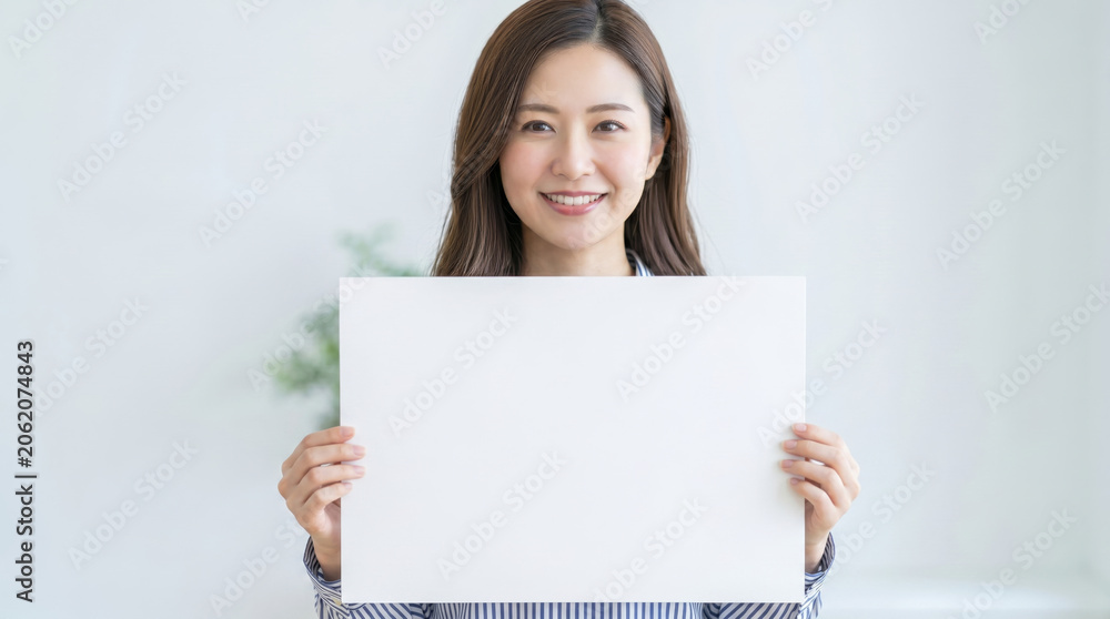 Naklejka premium 無地の白紙を両手で持つ笑顔の女性 コピースペース