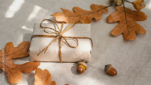 autumn leaves flat with brown paper wrapped giftbox on wooden background.ai  