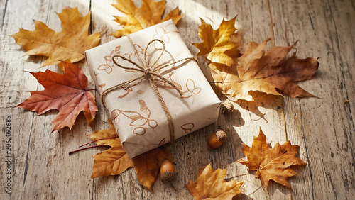 autumn leaves flat with brown paper wrapped giftbox on wooden background.ai  