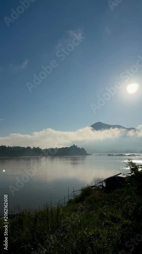 Vertical morning sun over misty river and mountains