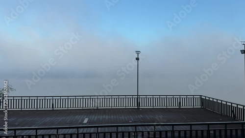 Empty wooden observation deck in thick morning river fog