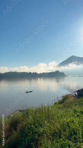 Vertical view of lone fisherman on misty river at sunrise