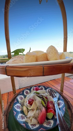 Close-up of authentic Thai spicy papaya salad or call Somtum and crispy pork cracklings platter set on wooden table by river