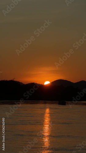Vertical golden sunset behind mountain over river