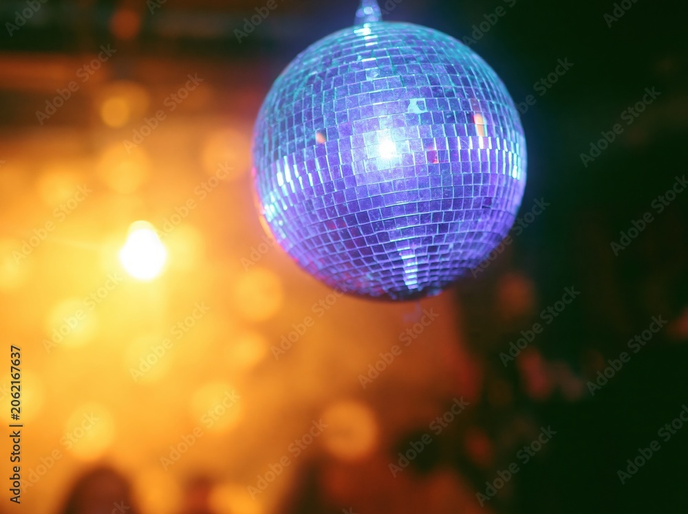 Obraz premium Purple mirrored disco ball hanging in a fiery party setting with glowing amber light for festive celebration and nightlife events