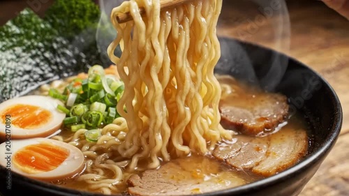 Steaming ramen bowl with pork slices, soft boiled egg and green onions