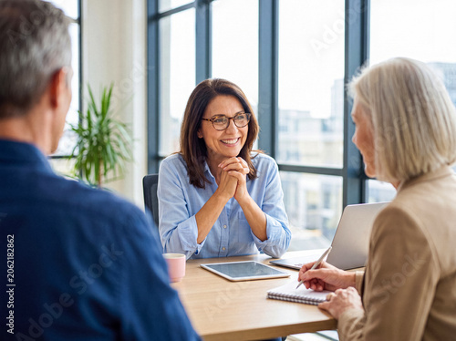 Tableau sur toile Mature financial advisor discusses future investment plans with senior couple in a modern office setting