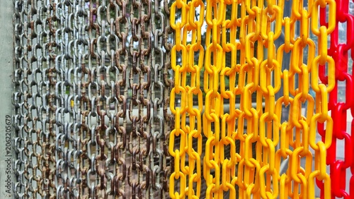 Rusty metal and bright yellow and red plastic chains hanging side by side