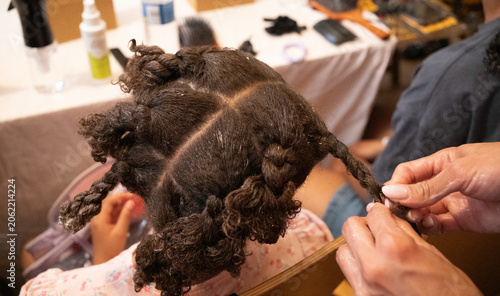фотографія Hair stylist hands braiding a child's natural black hair