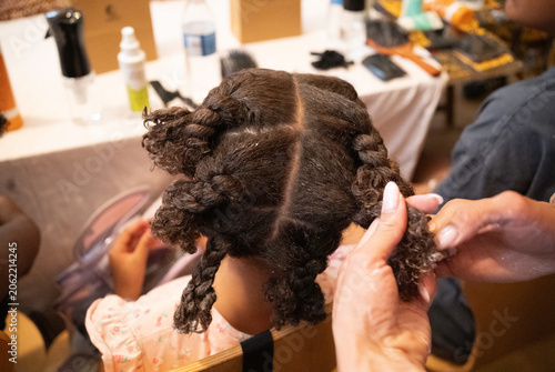 Принти на полотні Stylist hands braiding a young black girl's natural hair, creating protective st