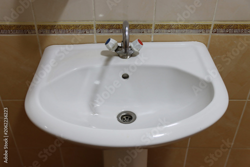 A white sink with a silver faucet and a drain