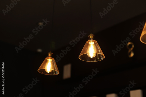 A filament light bulb with an orange light is suspended from the ceiling.