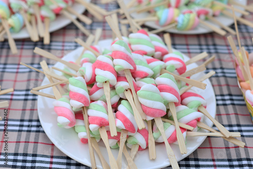 Marshmallows on sticks are placed on a plate.