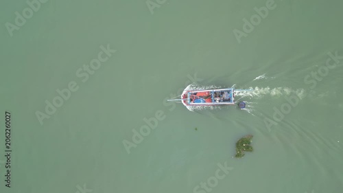 Aerial view of a traditional wooden boat cruising on the calm green water of the Thu Bon River in Hoi An, Da Nang, Vietnam.