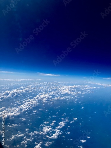 aerial view of fluffy white clouds and blue ocean under a deep dark blue sky