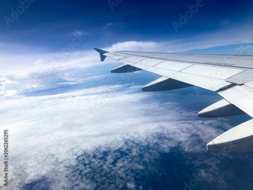 airplane wing flying above an extensive sea of clouds under a blue sky