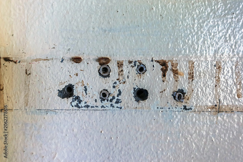 Close up of plastic wall plugs inside drilled holes on dirty concrete wall. Plastic dowels or wall anchors embedded into holes drilled in an old concrete wall. Home renovation and repair concept.