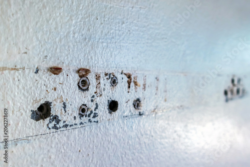 Close up of plastic wall plugs inside drilled holes on dirty concrete wall. Plastic dowels or wall anchors embedded into holes drilled in an old concrete wall. Home renovation and repair concept.