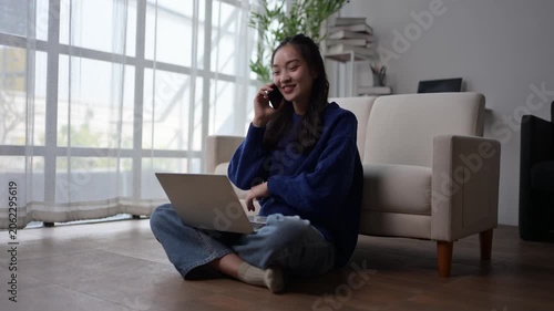 Young Woman Using Laptop and Talking on Phone in Cozy Living Room