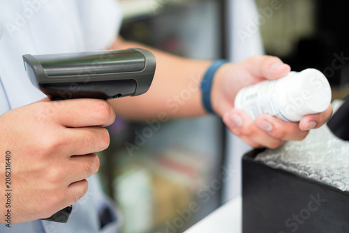 Foto Pharmacist Scanning Medication Bottle with Barcode Scanner in Community Pharmacy